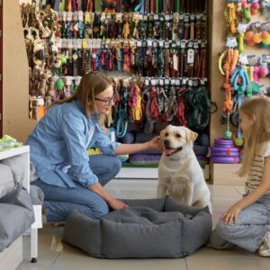 Mother and daughter choosing bed place for dog at pet shop